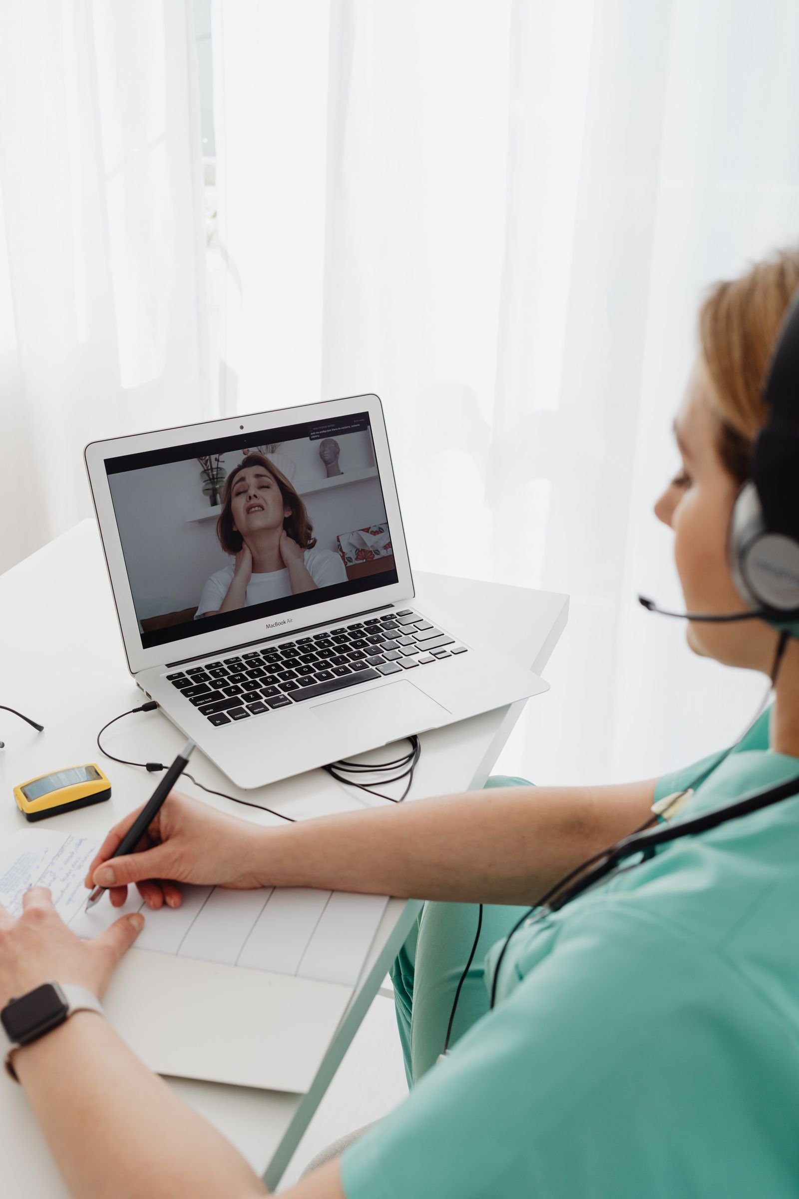 A mental health professional taking notes during a video consultation